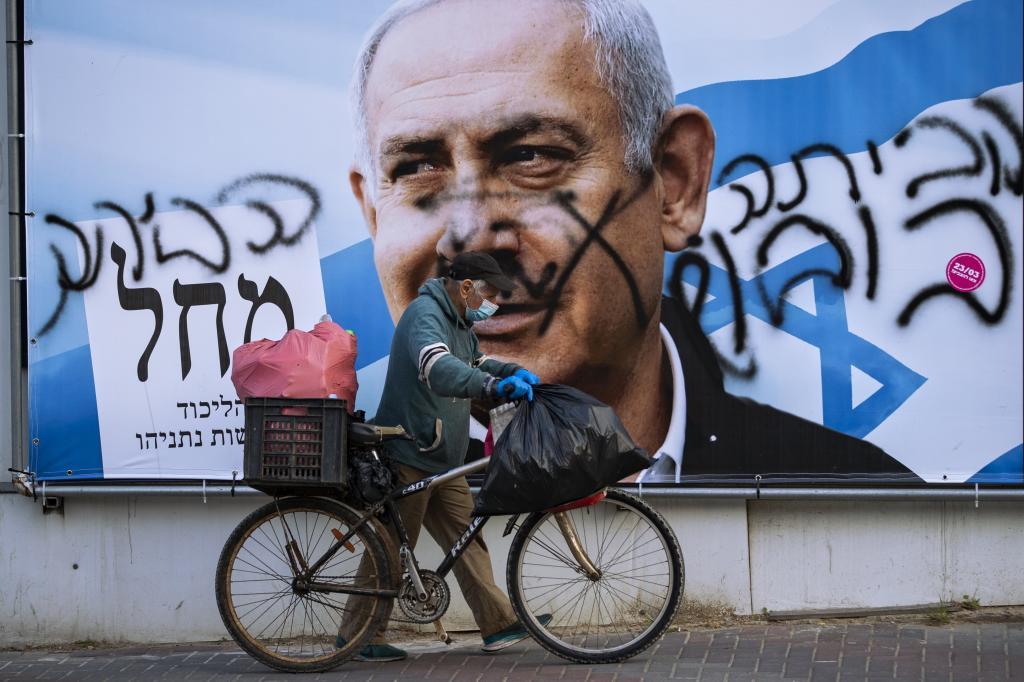 Un hombre camina por delante de un cartel de Netanyahu.