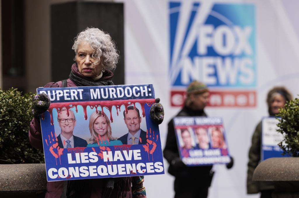 Una mujer protesta en la puerta de Fox News con un cartel que dice "Rupert Murdoch: las mentiras tienen consecuencias".